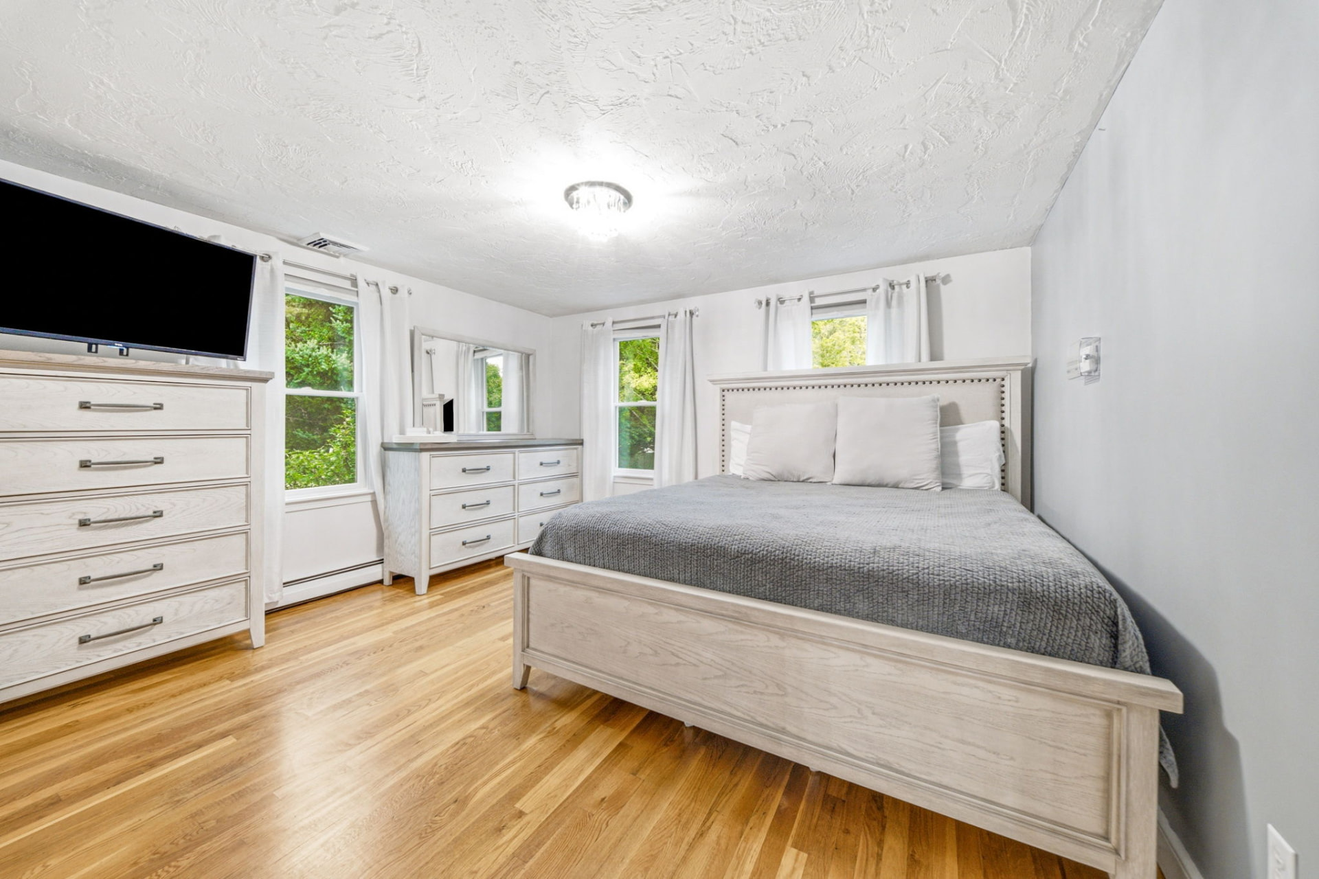 Spacious bedroom with hardwood floors and king bed