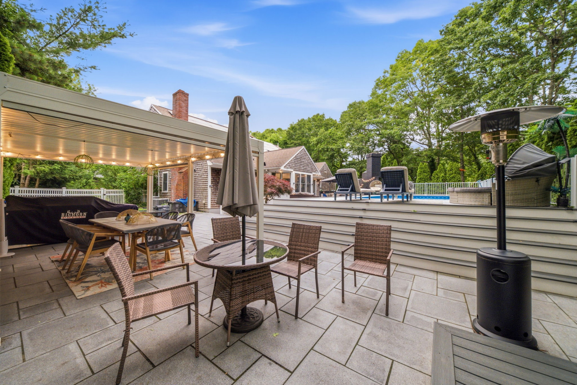 Covered pergola dining area and bluestone patio beside the pool deck