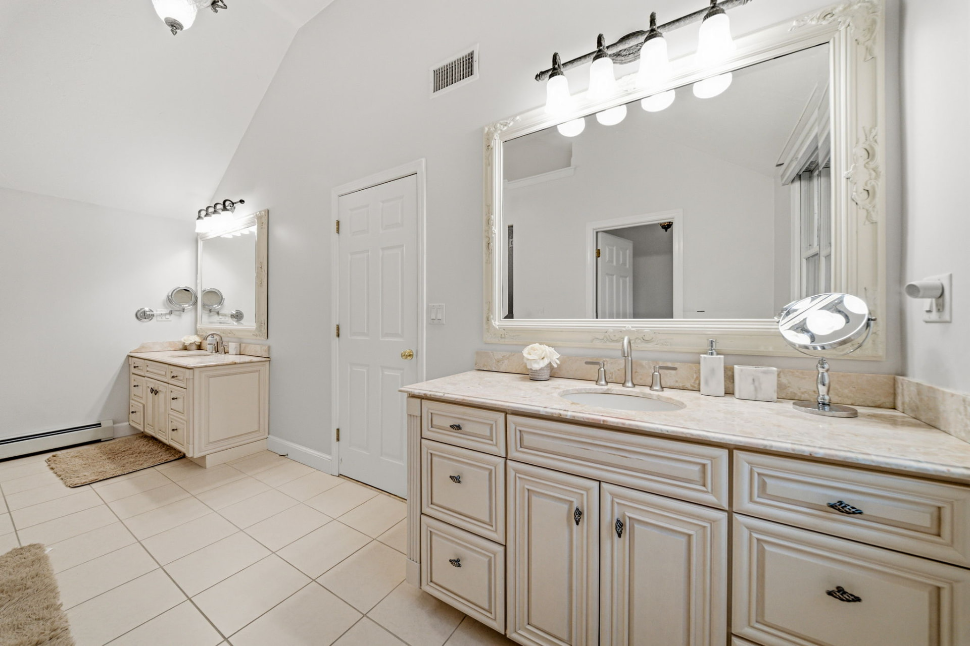 Primary bath with dual vanities, stone counters and vaulted ceiling