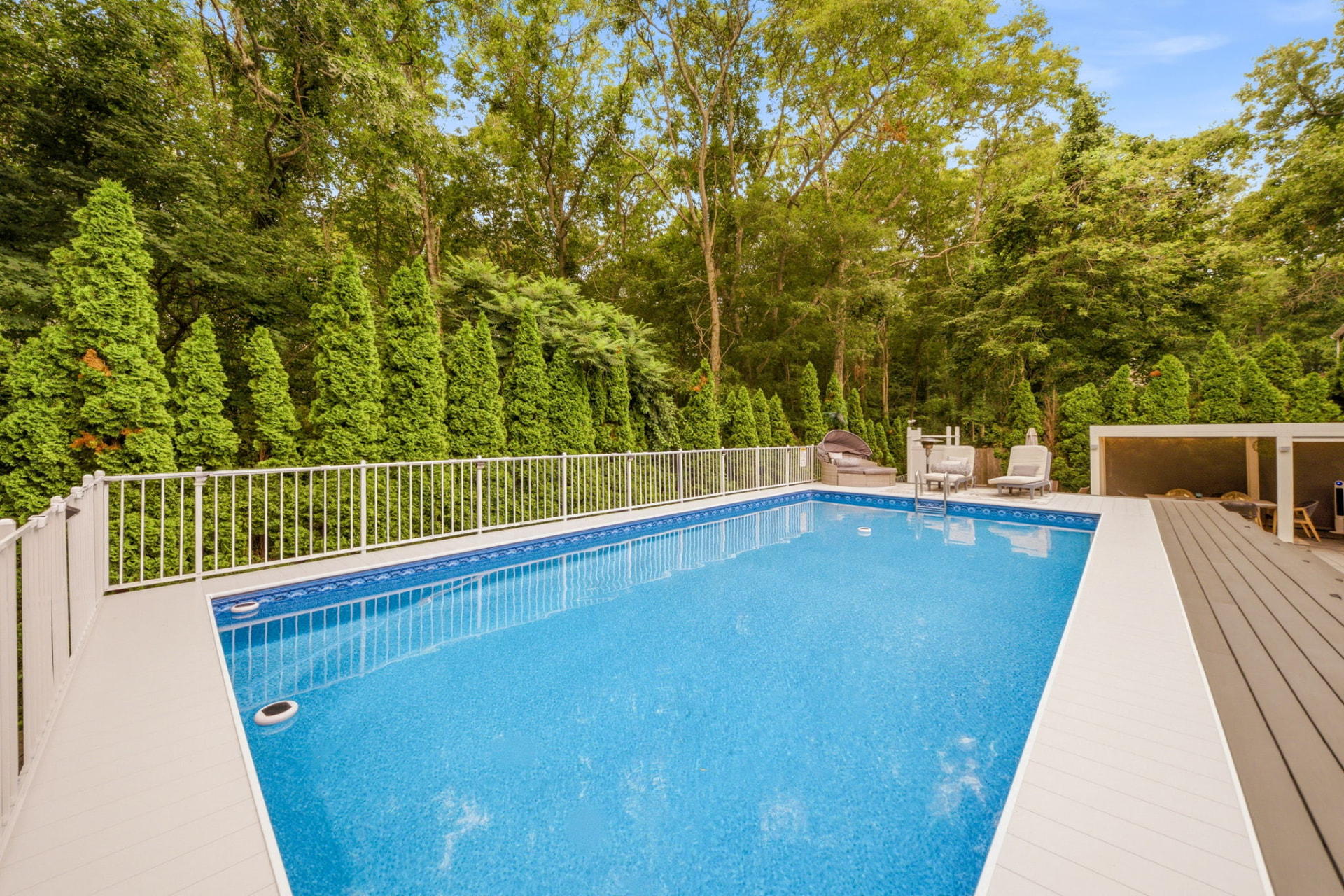 Full-length view of the heated above-ground pool framed by evergreens